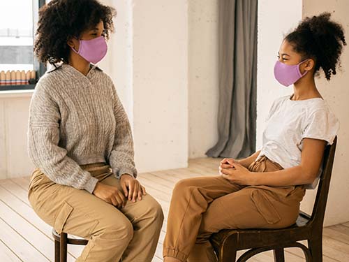 two people sitting masked looking at each other