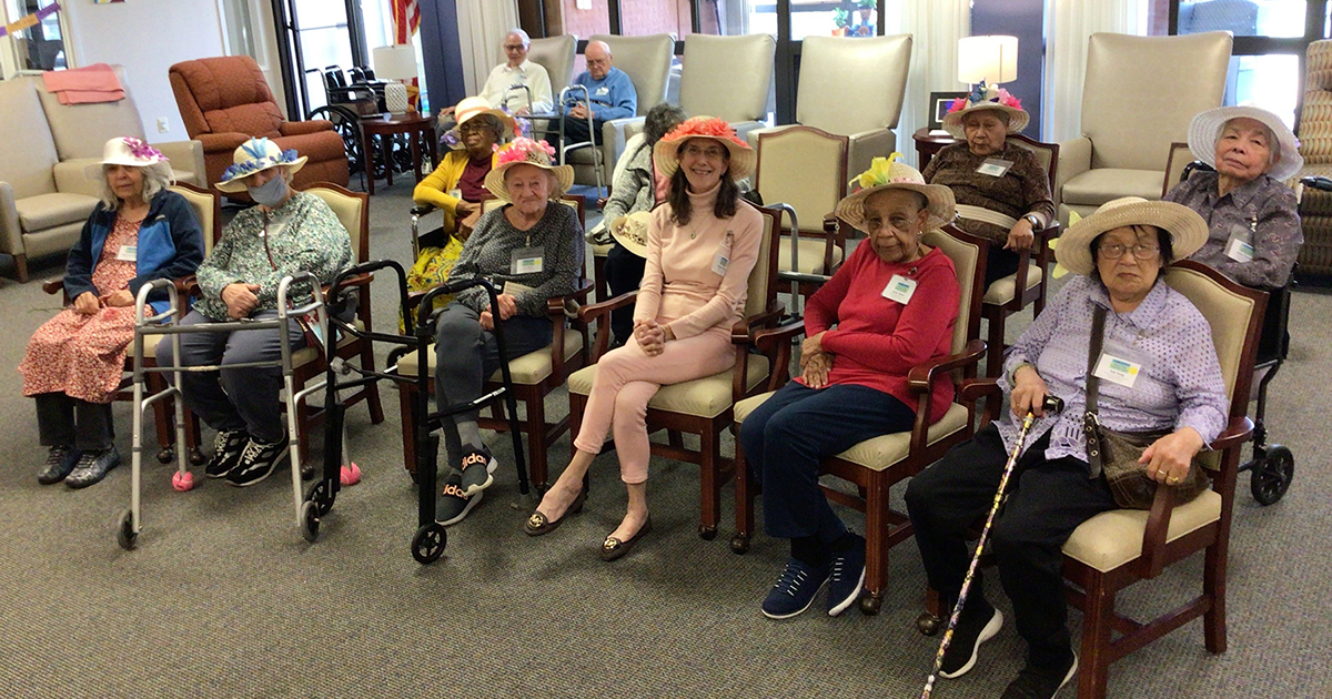Photo of diverse group of older adults sitting in a row smiling at Adult Day Care Program