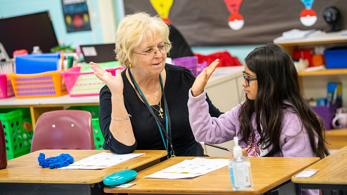 Photo of Bunnie Cooper slapping a high five with a student in the classroom. 