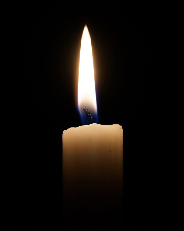 Photo of a candle flame in a dark room.