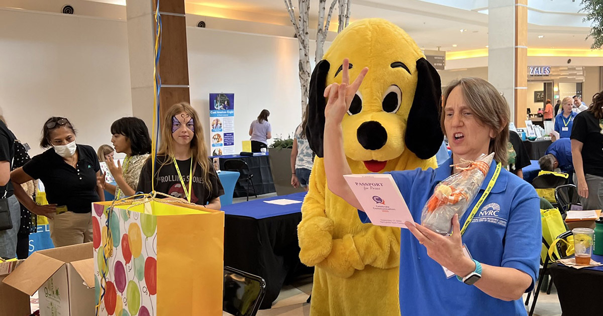 An NVRC staff person with the Yellow Dog mascot at Celebrate Communication 2022.