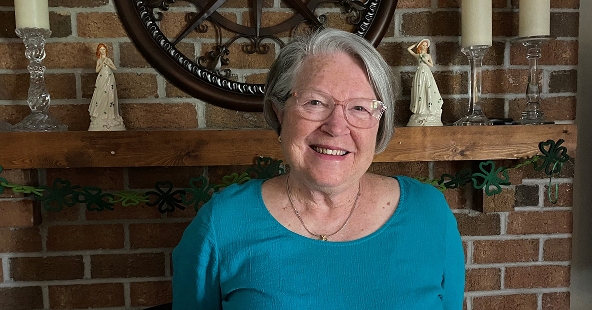 Photo of Dorothy Keenan standing in front of a fireplace in her home.