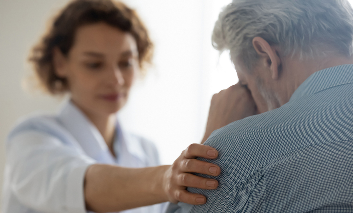 Sad older man being comforted by an adult woman. 