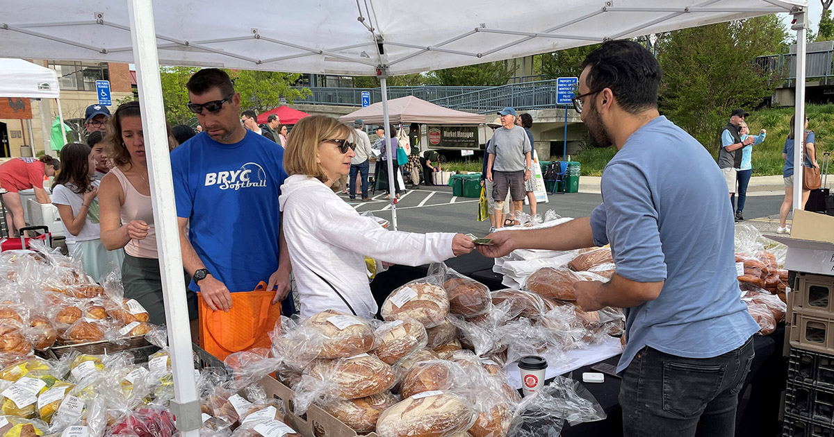 People line up at a Fairfax County Farmers Market to buy baked goods.