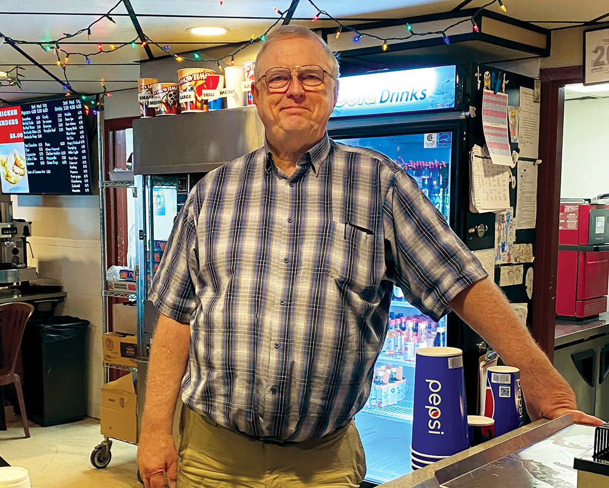 Photo of Mark O'Meara standing behind the concessions desk at Cinema Arts Theatre