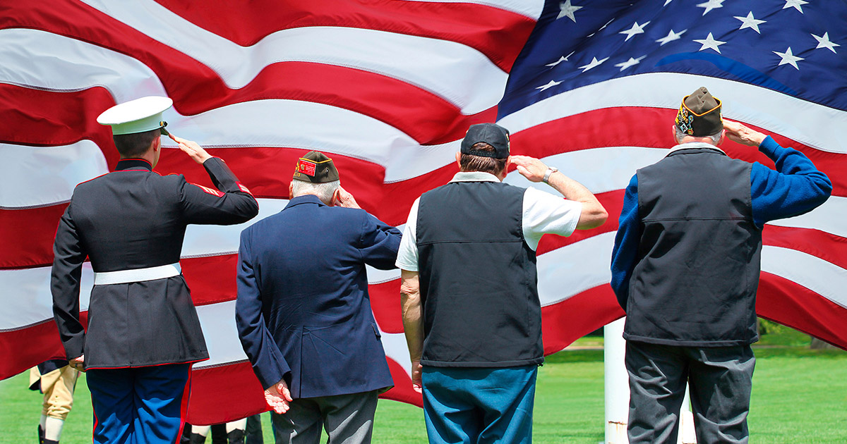 Photo of a military officer and three veterans saluting the U.S. flag.