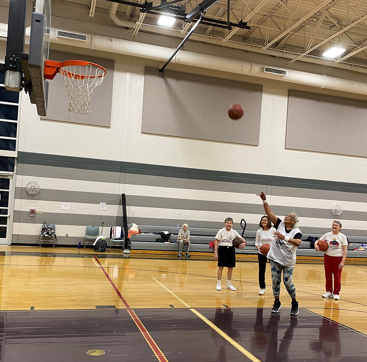 A photo of Vivian Robertson shooting a basketball while other players watch. 