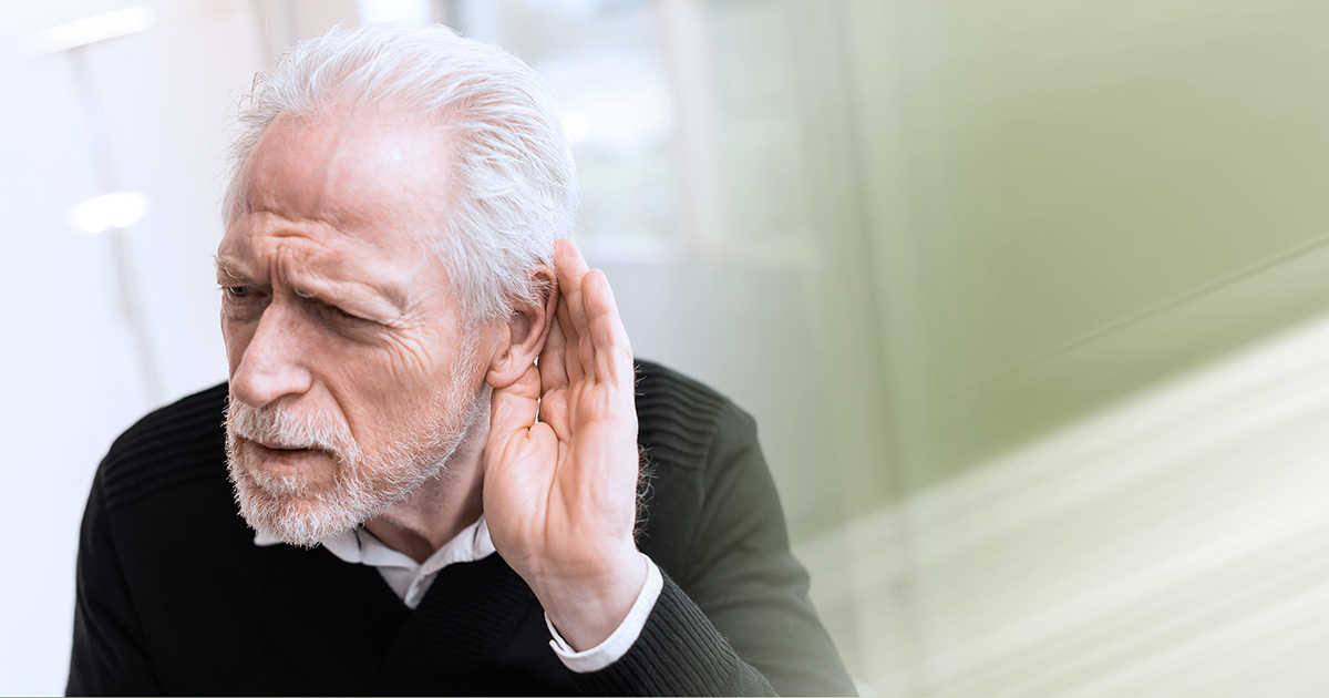 Photo of older white man holding his hand to his ear trying to hear