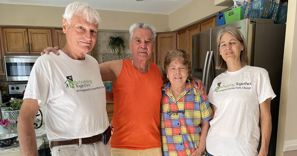 Two Rebuilding Together volunteers standing with Mr. and Mrs. C in their kitchen.