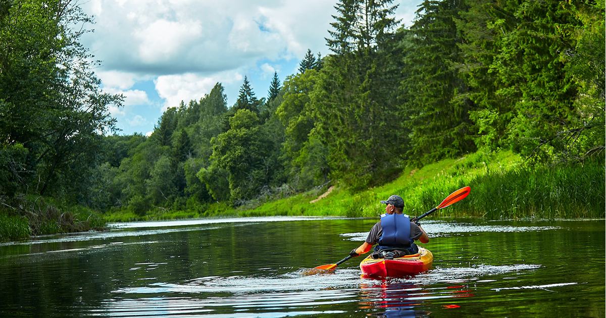 A man in a kayak paddling in an unknown body of water.