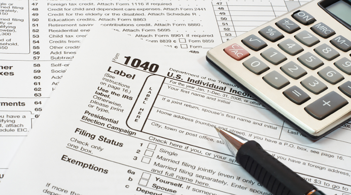 Photo of a 1040 federal tax form, a pen, and a calculator