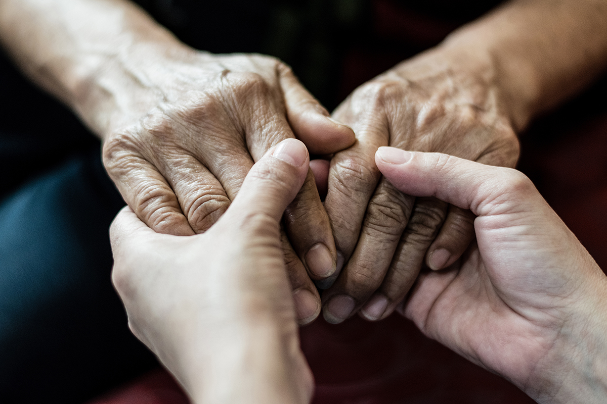 Photo of a pair of hands holding a second pair of older hands.