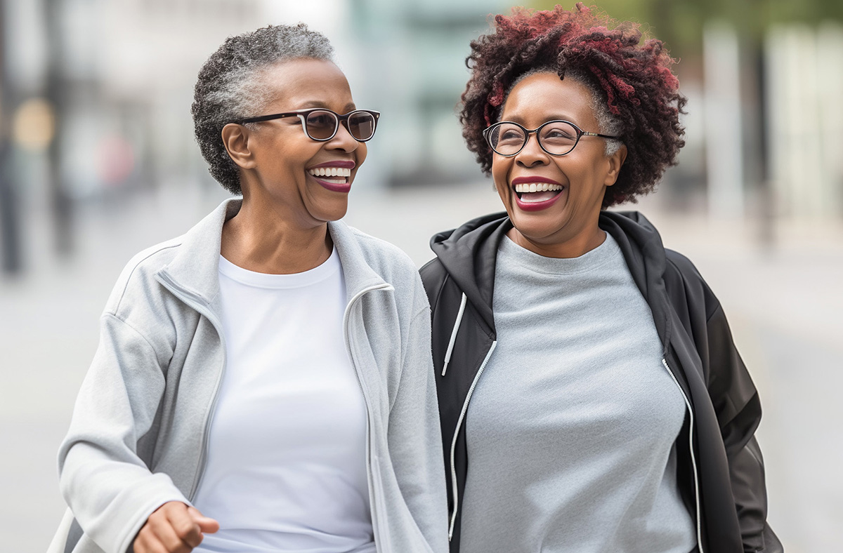 Photo of two older African American women smiling and walking together. 