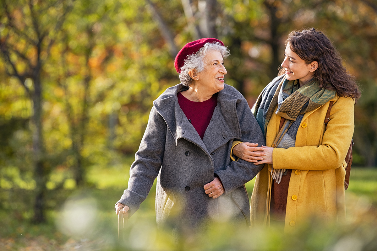 Photo of a young white woman walking outdoors with an older white woman during the fall.