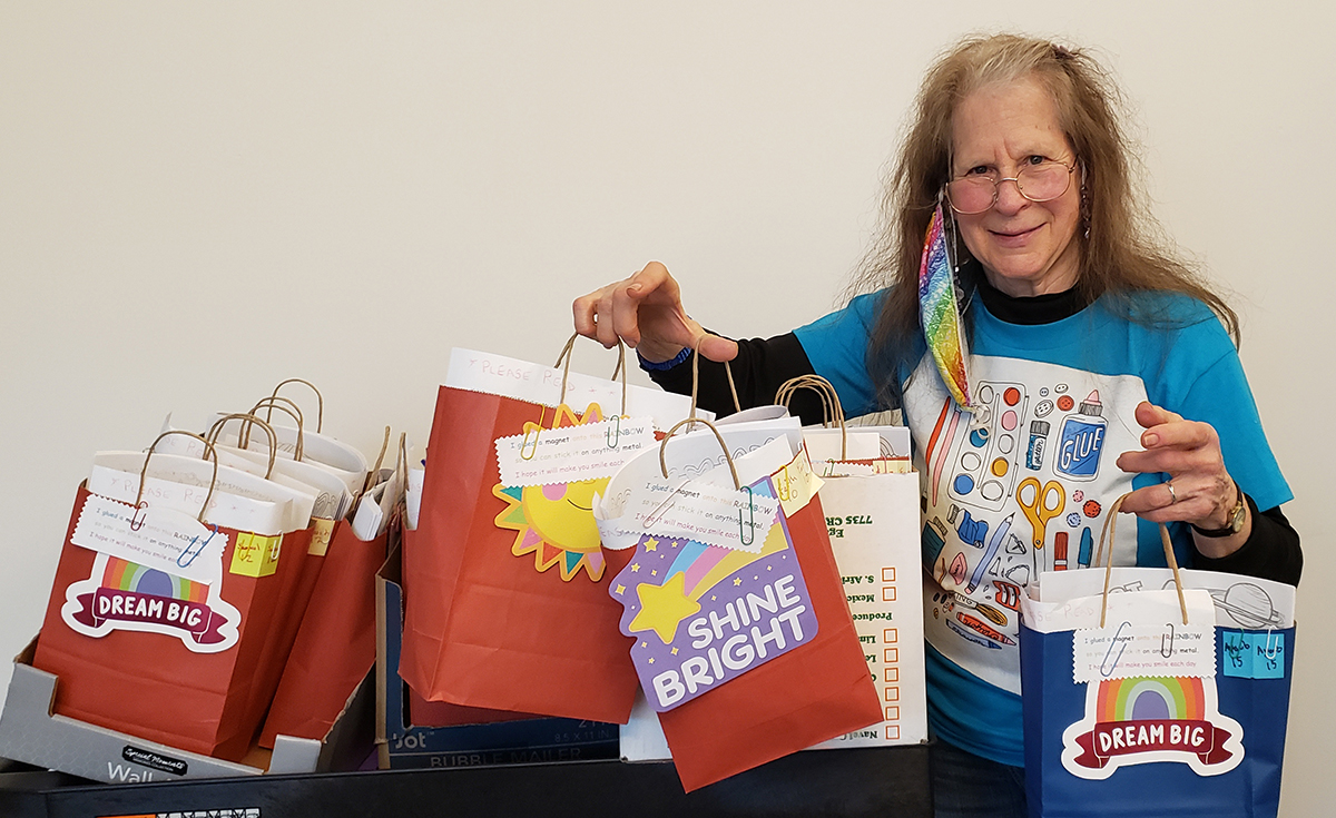 Photo of Gail Ruf delivering bags of arts and craft supplies to a shelter.