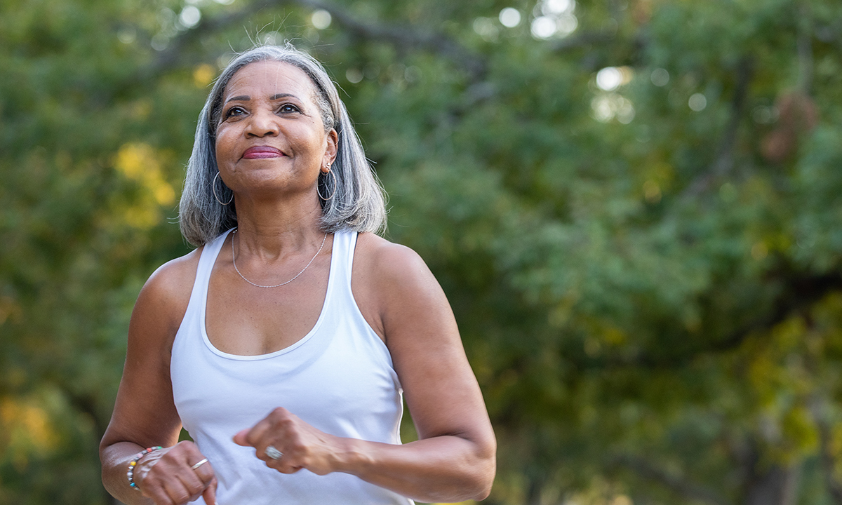 Photo of an older woman smiling and walking outdoors. 