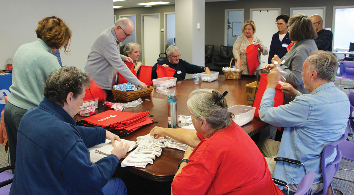 RSVP volunteers working together to pack 100 hospital comfort kits for the American Red Cross.