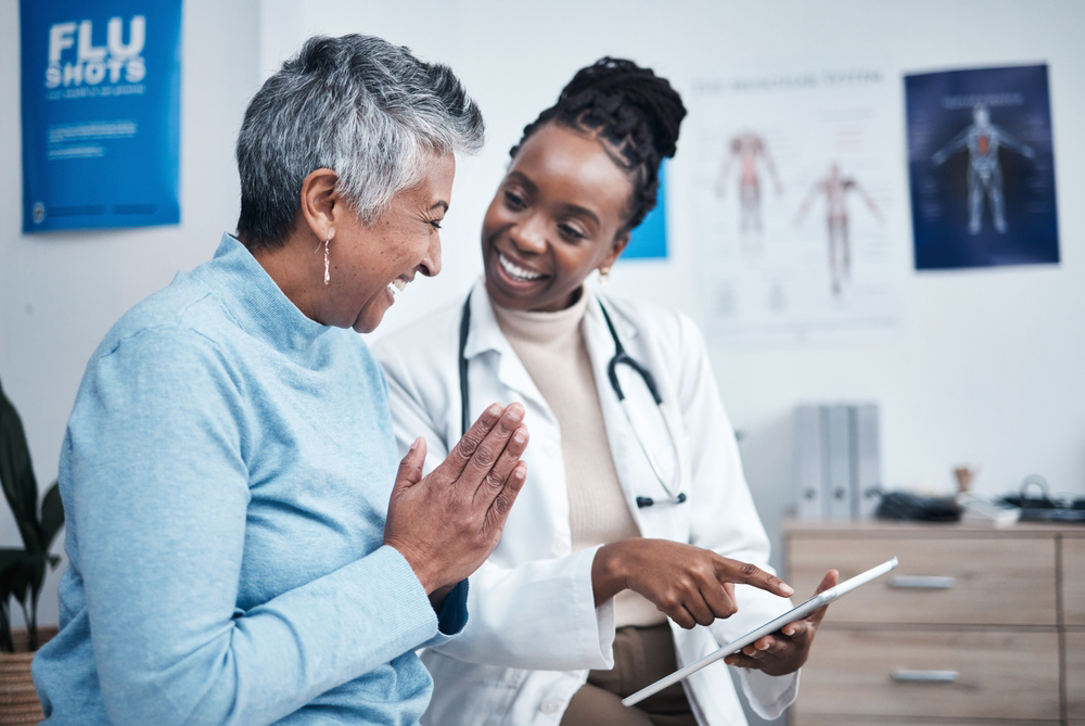 Photo of an older woman talking with her doctor in an exam room.