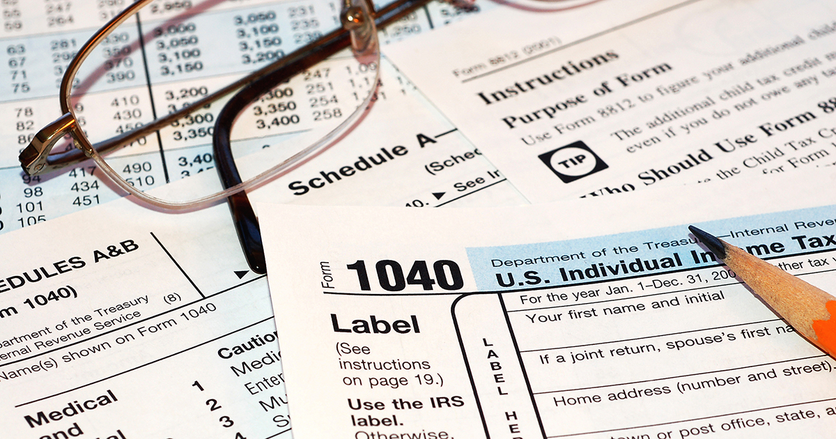 Photo of a 1040 tax form with a pencil and a pair of glasses resting on it.