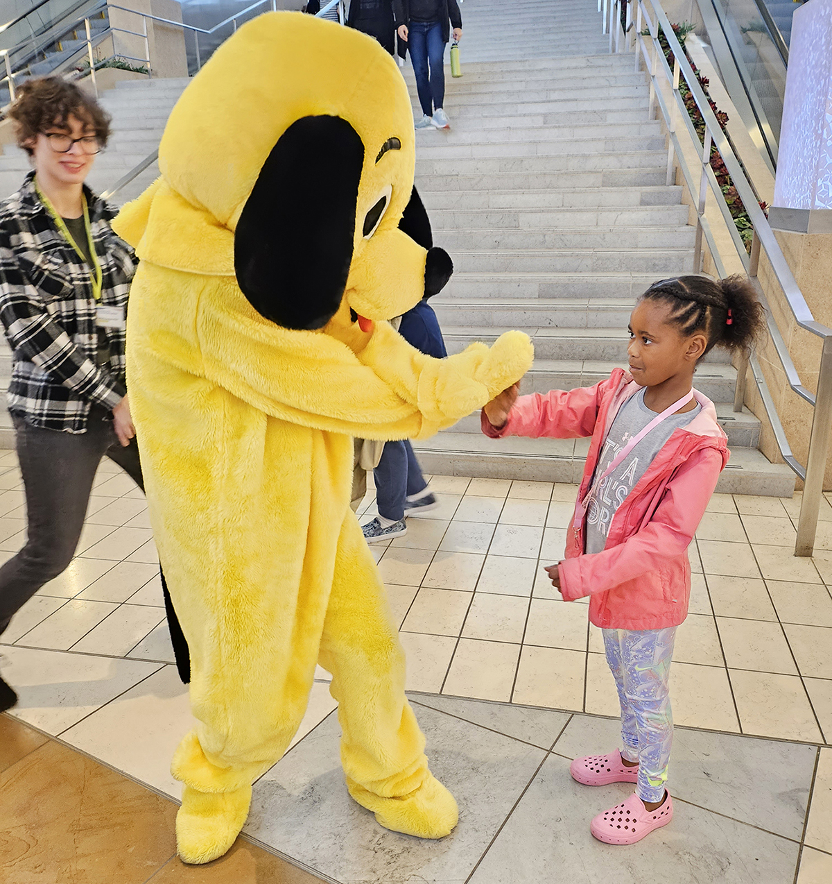 Photo of the Yellow Dog mascot with a little girl at Celebrate Communication 2023. Photo courtesy NVRC.