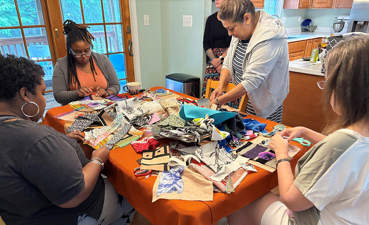 DSVS staff sewing quilt blocks together around a kitchen table.