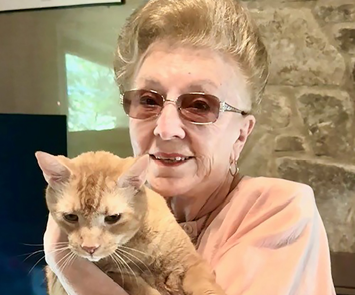 Elaine Miletta holding an orange cat and smiling.