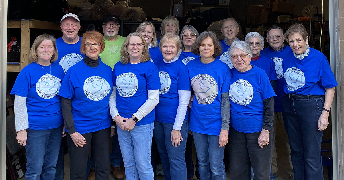 Gracing Spaces volunteers stand in the doorway of their facility wearing matching shirts.
