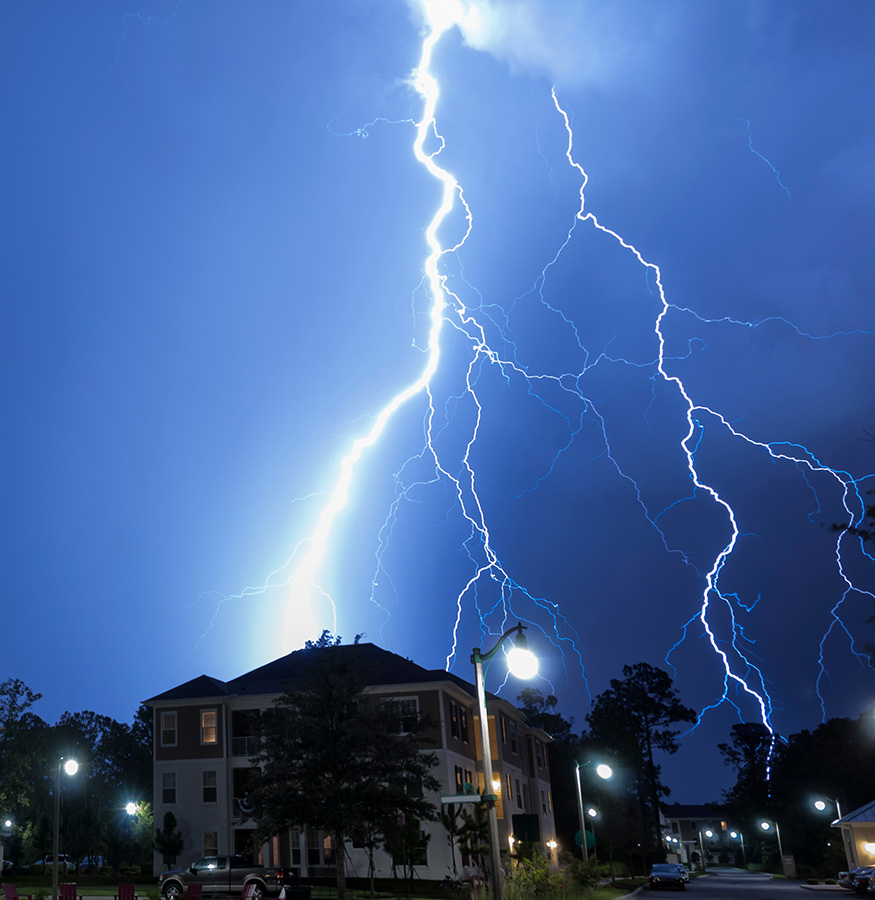 Lightning lights the night sky over homes.