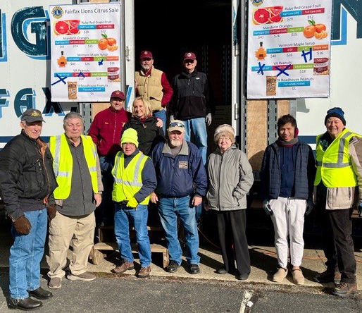 Fairfax Lions Club members standing in front of a large trailer full of citrus as they prepare to distribute it to buyers.