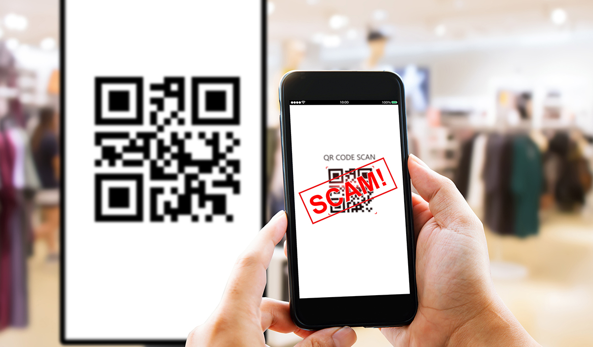 Photo of a person holding a phone up to scam a QR code while a warning message "SCAM!" appears on the screen.