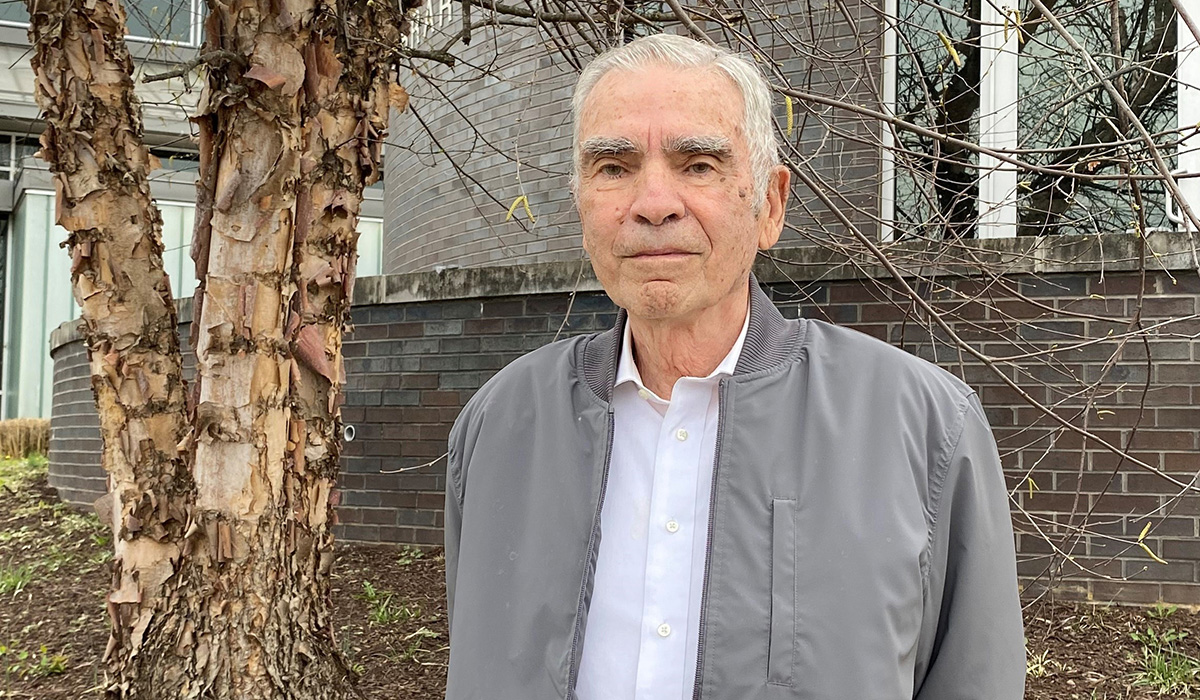 Photo of Dr. Russell Rayman standing outdoors in front of Martha Washington Library in Fairfax County.