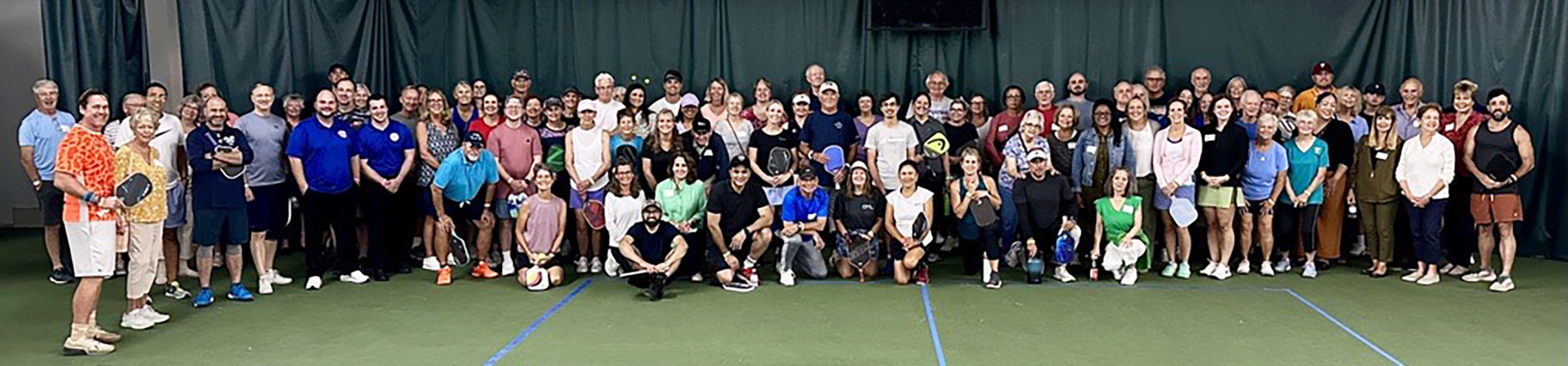 Participants of the 2024 Pickleball fundraiser pose together on a pickleball court.