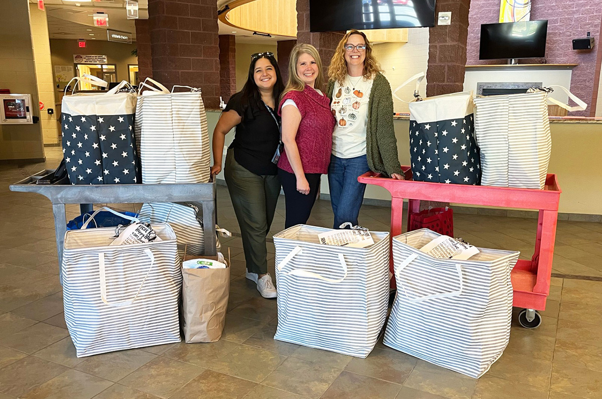 DFS staff stand next to two cards filled with housewarming baskets, while other baskets are arranged on the floor in front of them.