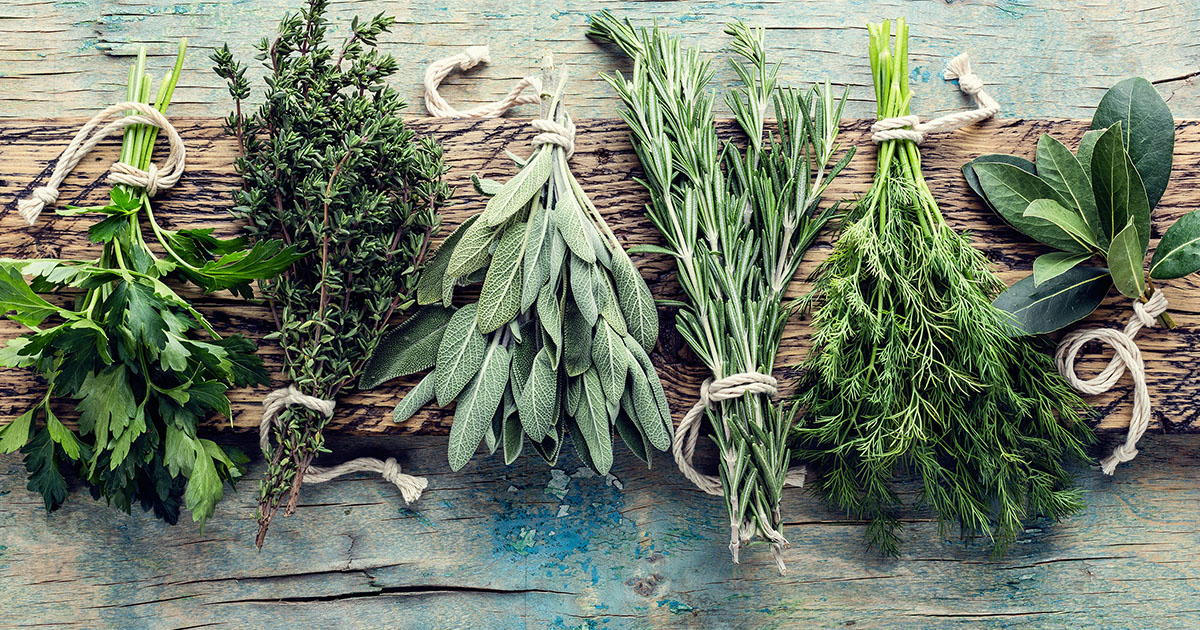Bundles of fresh herbs sit on a rustic wooden surface.