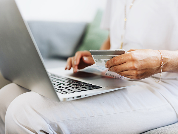 person sitting using laptop and holding credit card