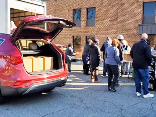 people loading vehicle trunk with boxes of food