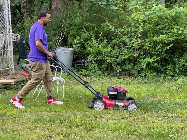 Volunteer mows a lawn.