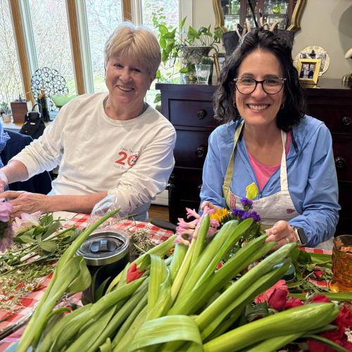 two women sitting in front of flowers smiling