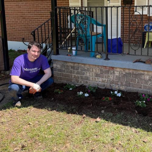 volunteer next to flowerbed