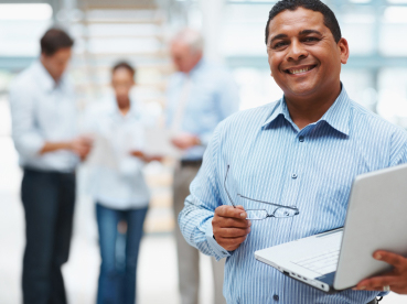 person holding laptop with people in background