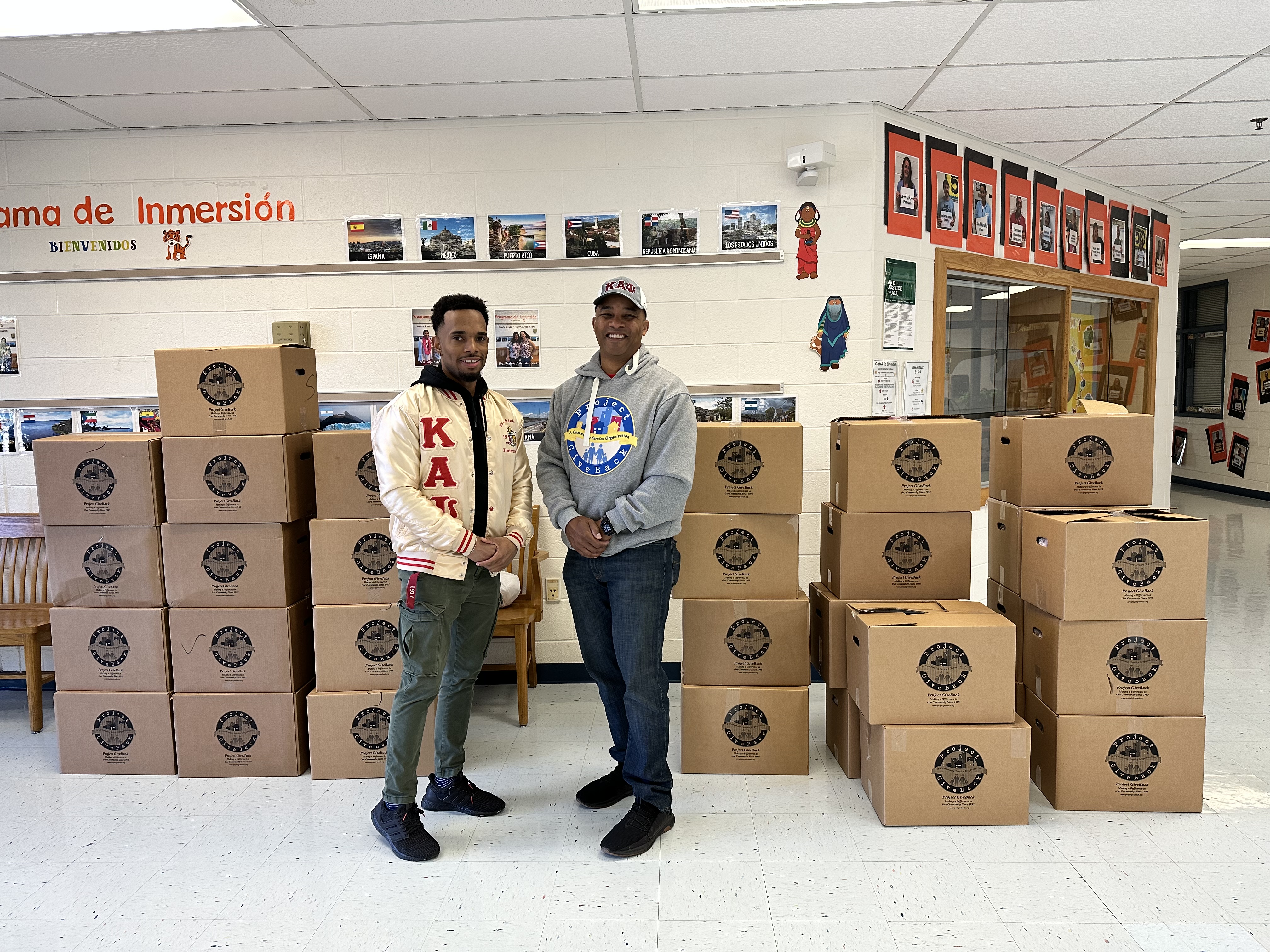 Two men in front of food donation boxes