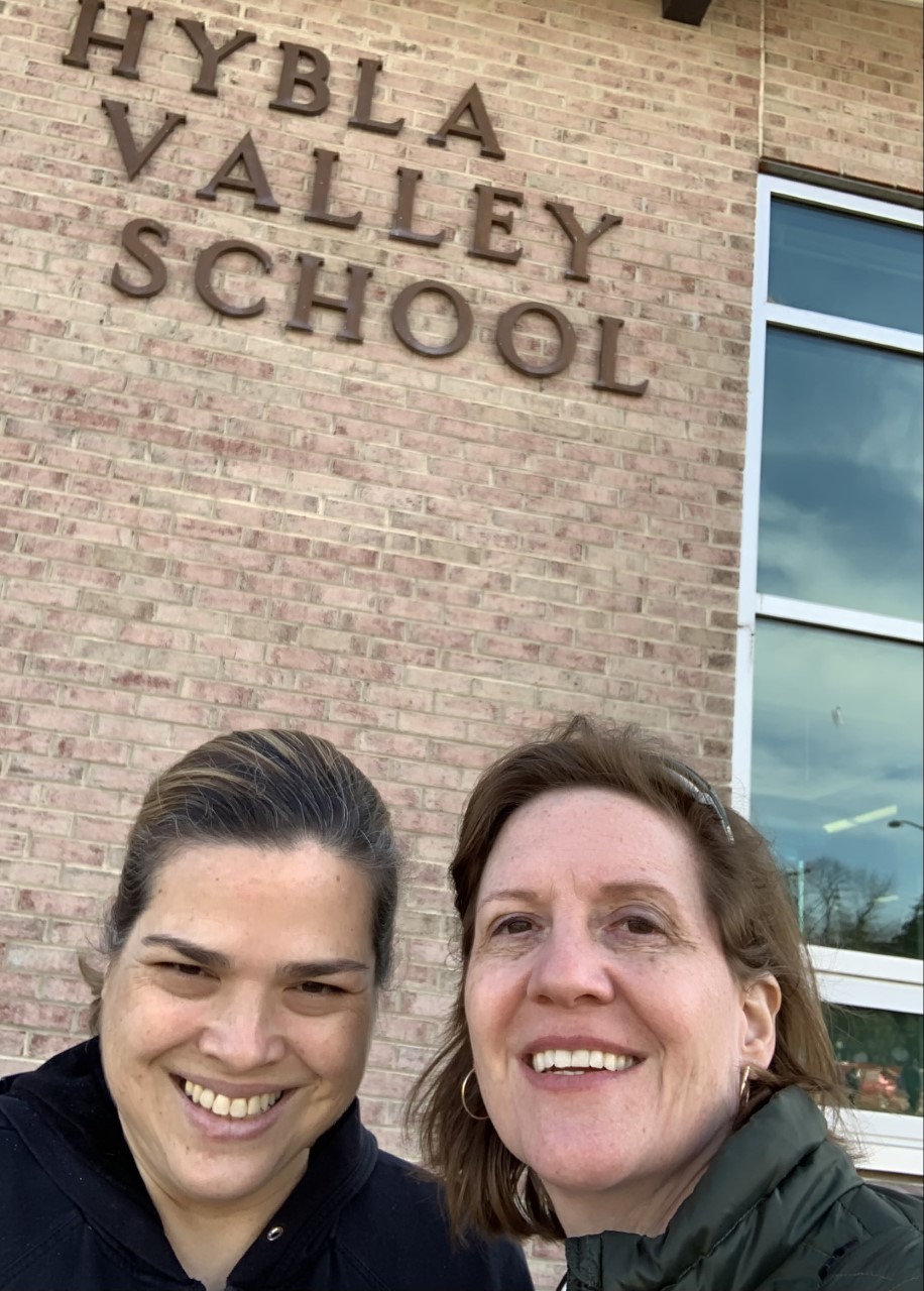 Two people taking a selfie in front of a school