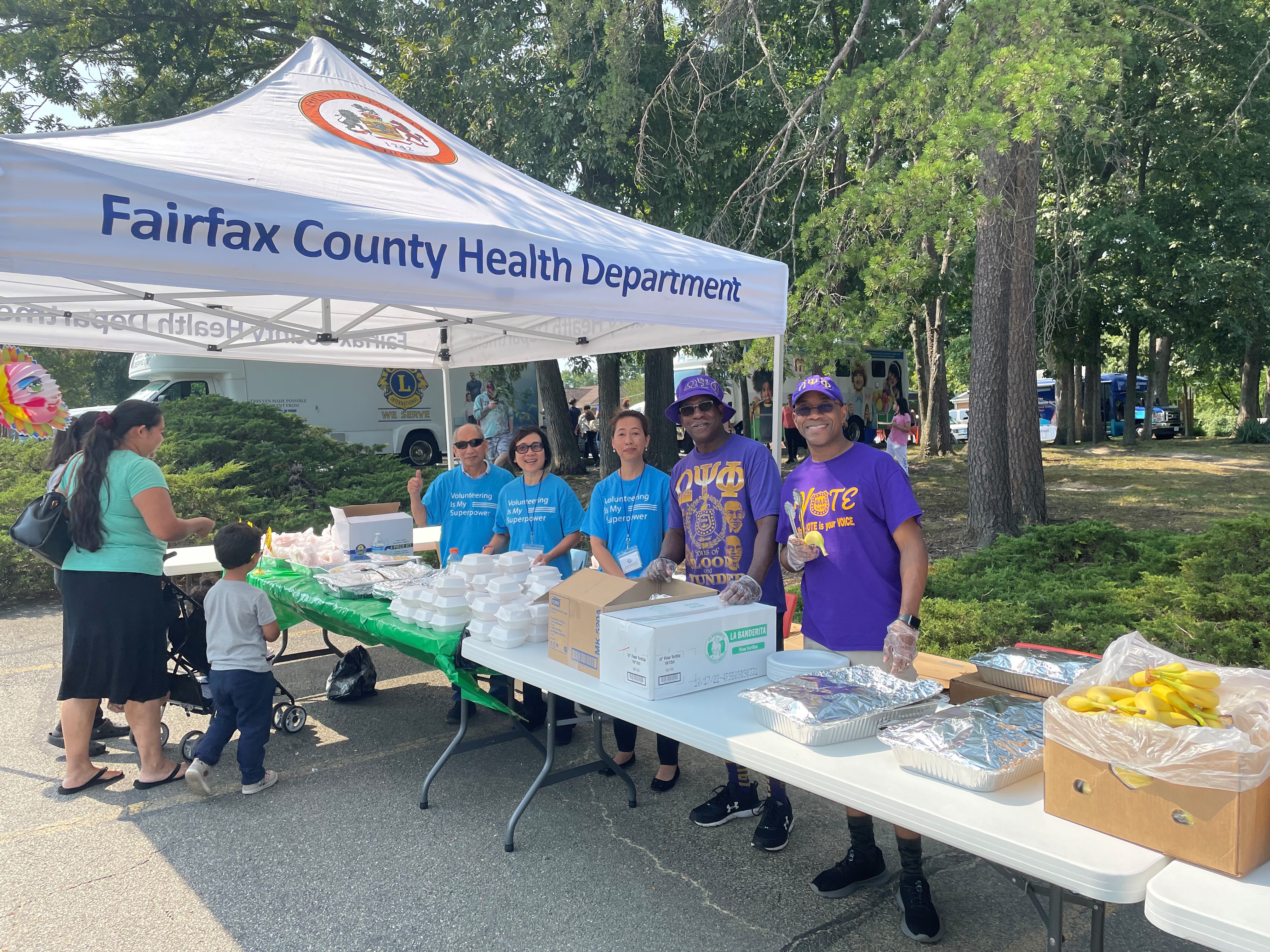 Omegas and Asian American Community Center volunteers serving food 