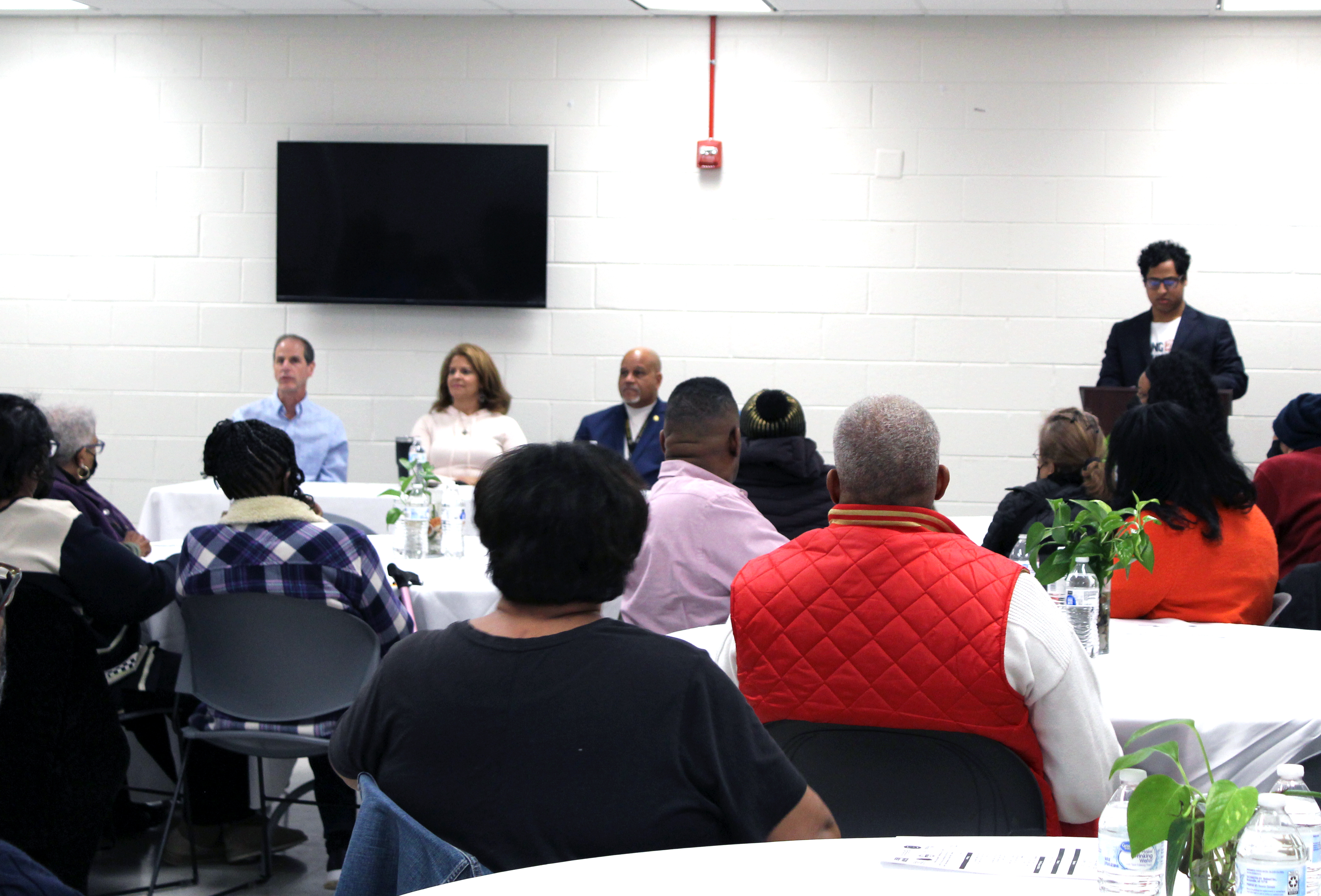 The panel engages with a room full of community members.