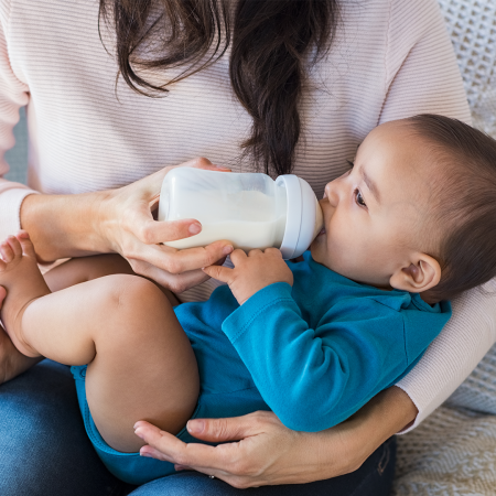 A cradled baby drinks from a bottle.