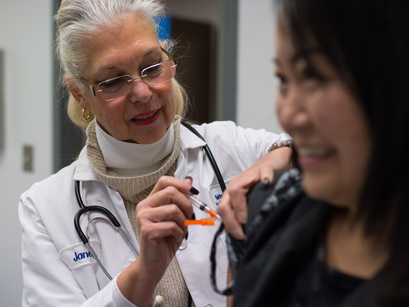 Female nurse vaccinates female patient in upper right arm