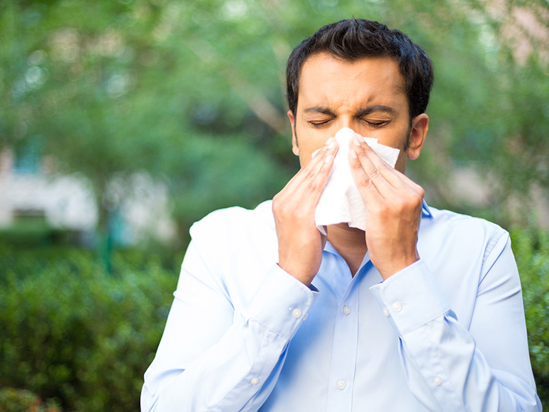 Man covers his mouth and nose with a tissue while sneezing