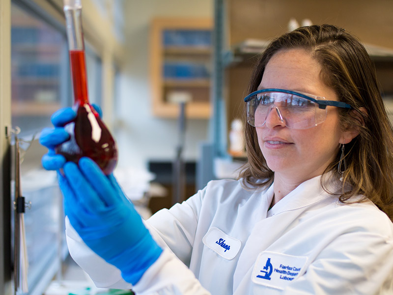 Female lab professional holds up lab flask