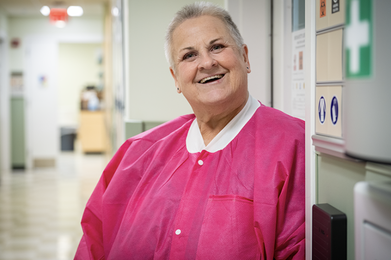 Photo of smiling Mary Louise Kolodziej wearing a bright pink lab coat in the lab.