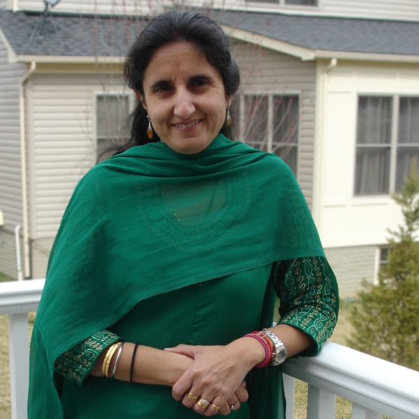 Photo of a smiling Savita Sood standing outside wearing green.